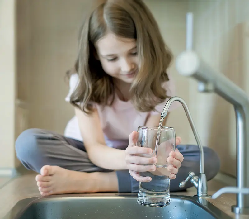 A child holding a glass under a fountain 
